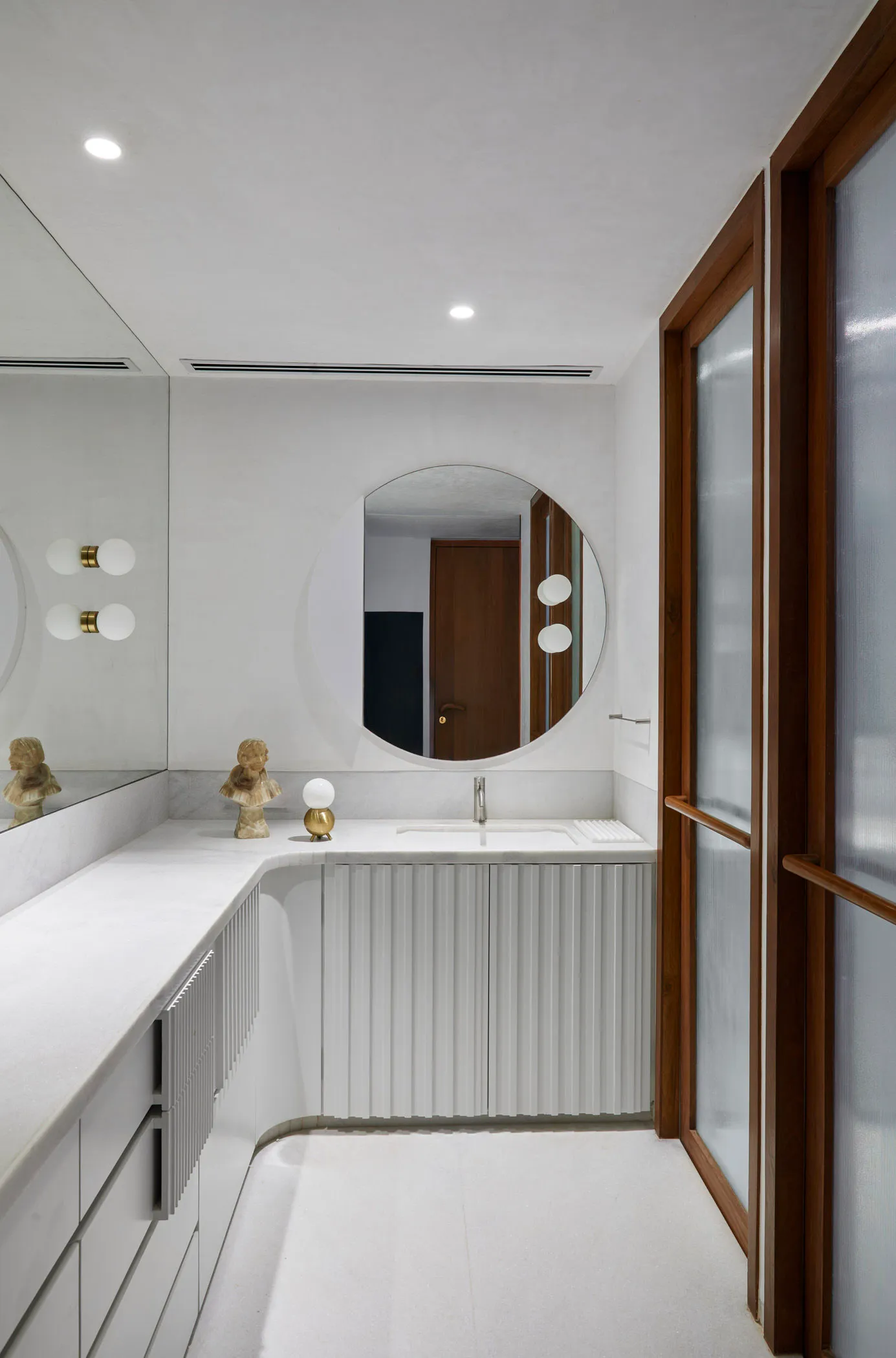 Modern bathroom featuring marble and concrete materials with a circular mirror and minimalist design.