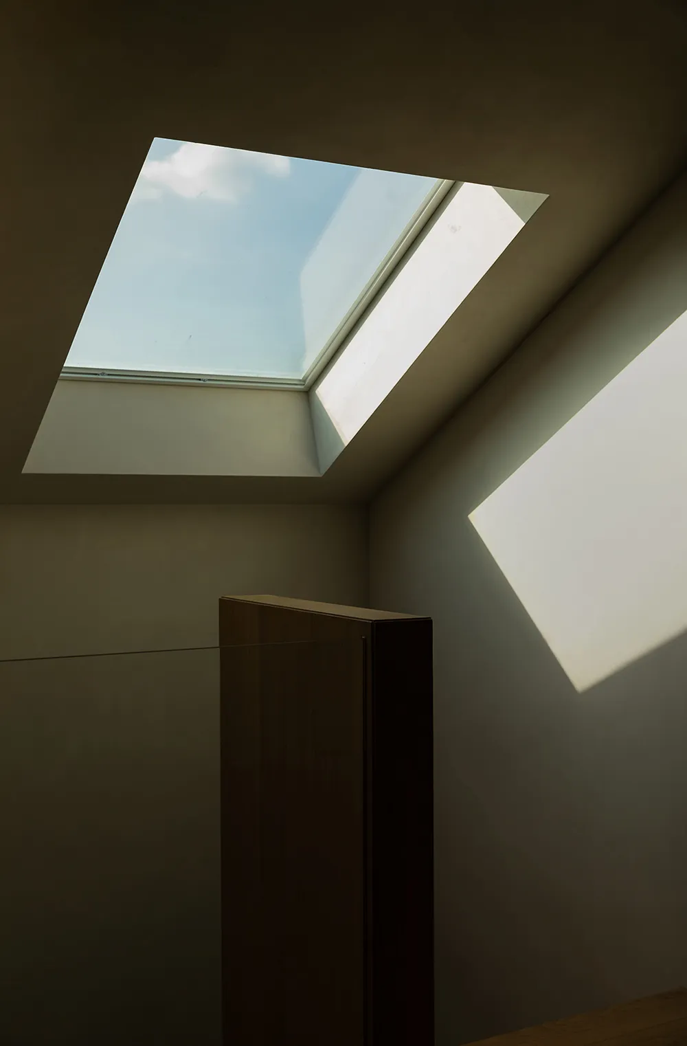 A minimalist interior showing a white ceiling with a metallic cabinet.