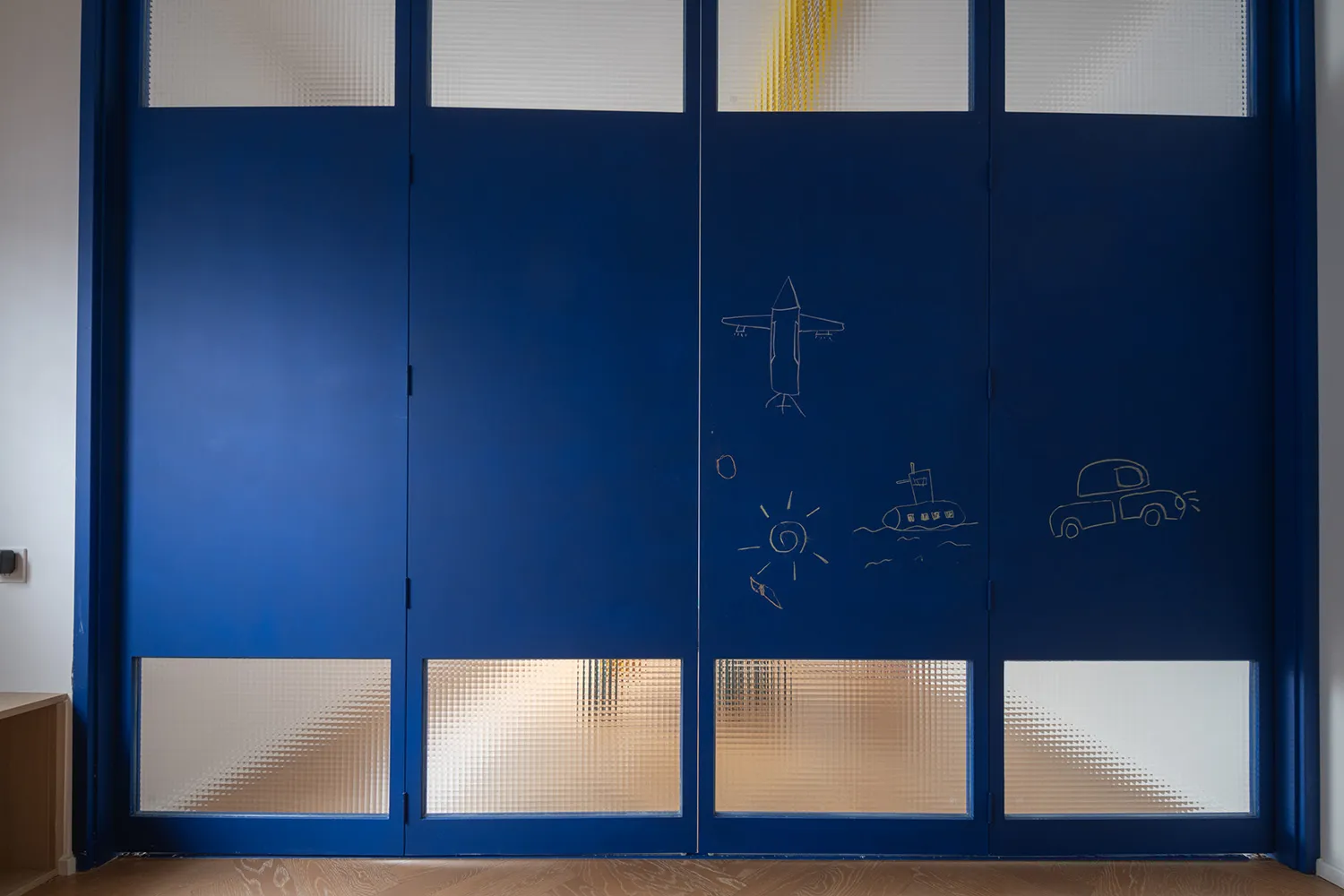 A blue wooden double door with glass panels and simple white doodles.