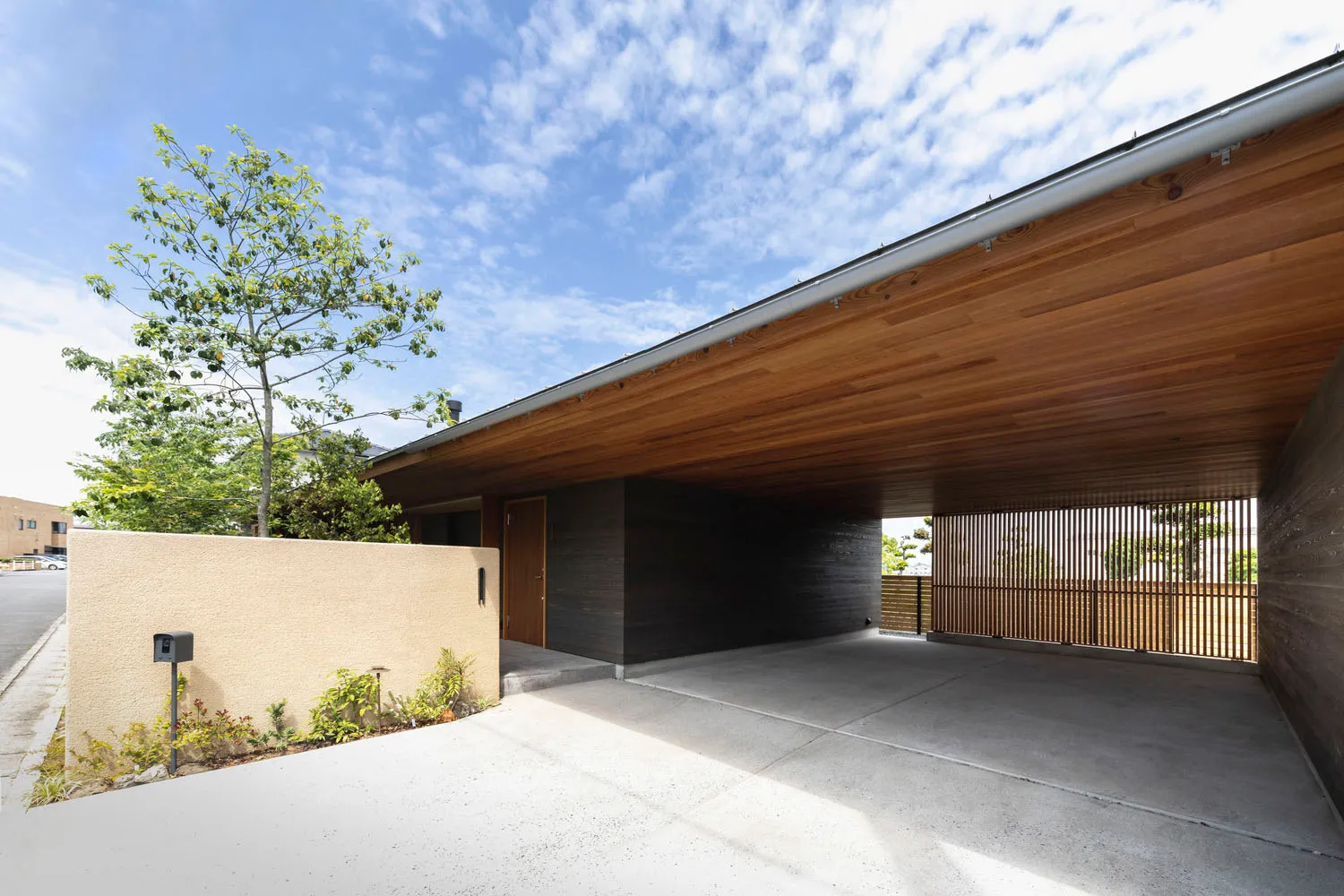 Concrete driveway with wooden carport and entranceway.