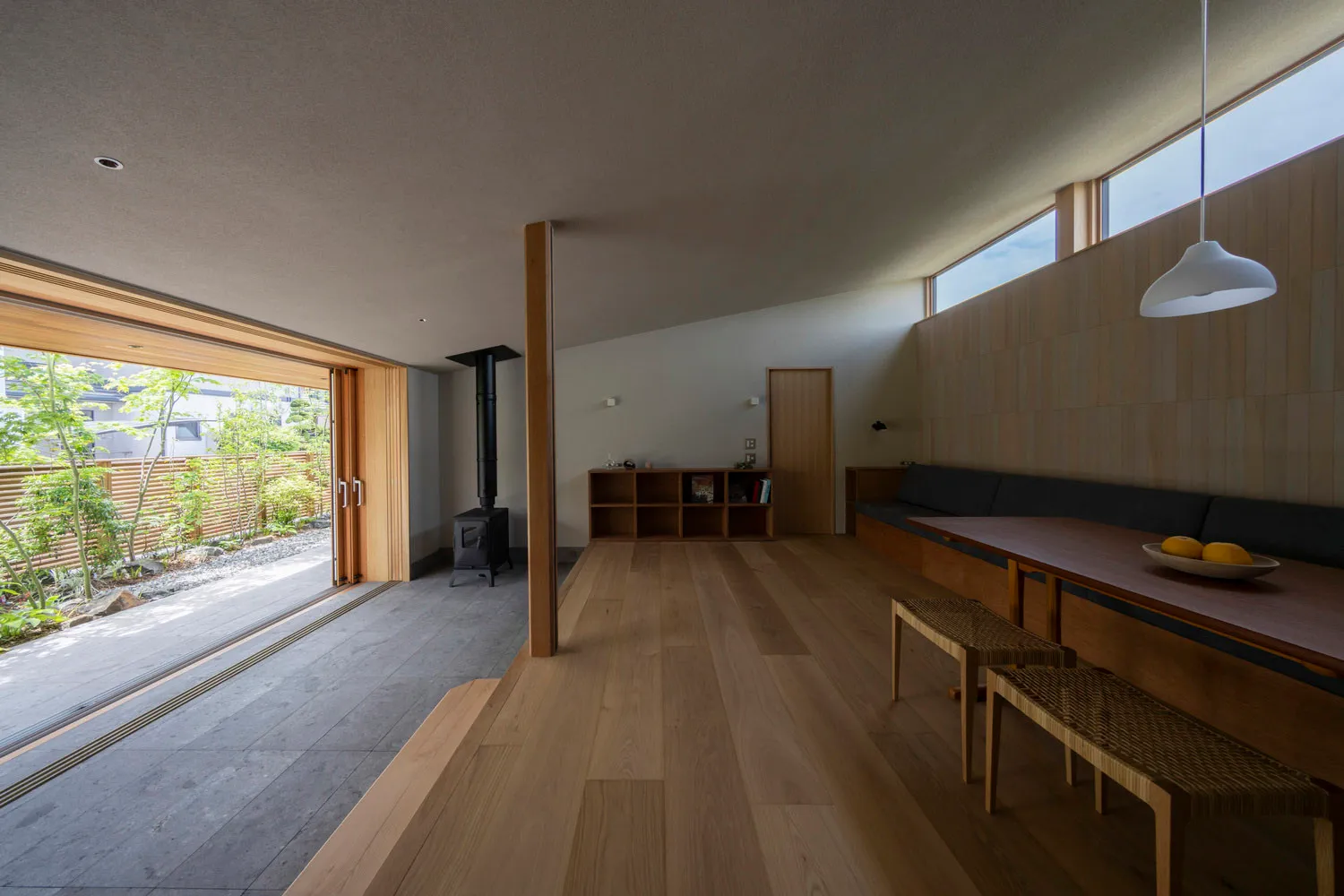 A modern living room with wooden flooring and a view of the garden.
