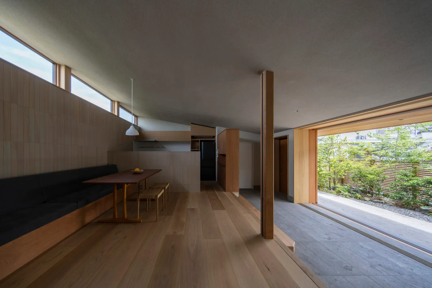 A modern kitchen with a wooden bench, concrete floor, and minimalist design elements.