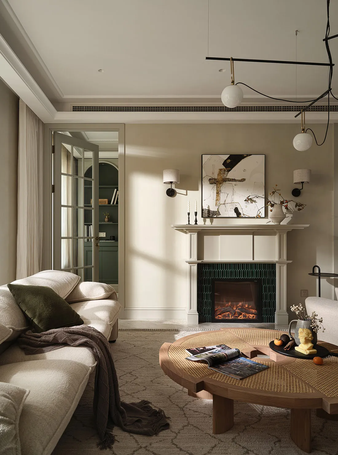 Modern living room featuring a comfortable beige sofa with green cushions, a round wooden coffee table with magazines and fru
