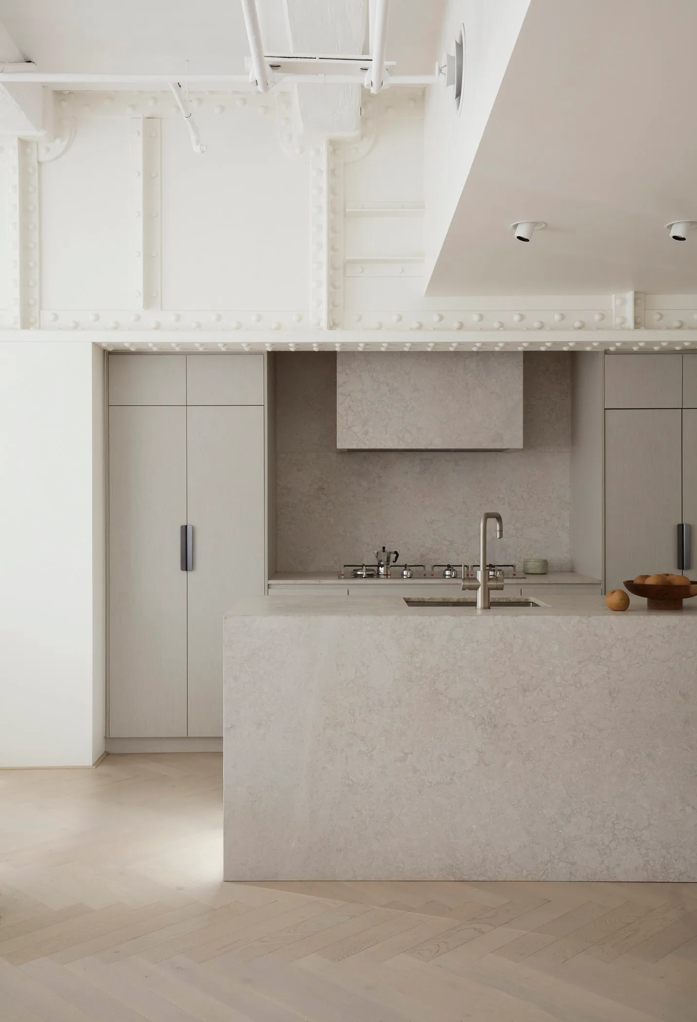 Modern, minimalist kitchen featuring a concrete countertop and sleek, gray cabinetry.