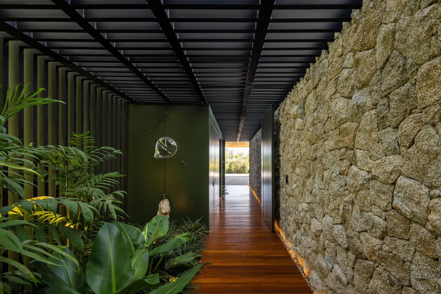 A modern minimalist hallway with stone and wooden walls and a wooden floor, featuring a sleek design with a glass light fixtu