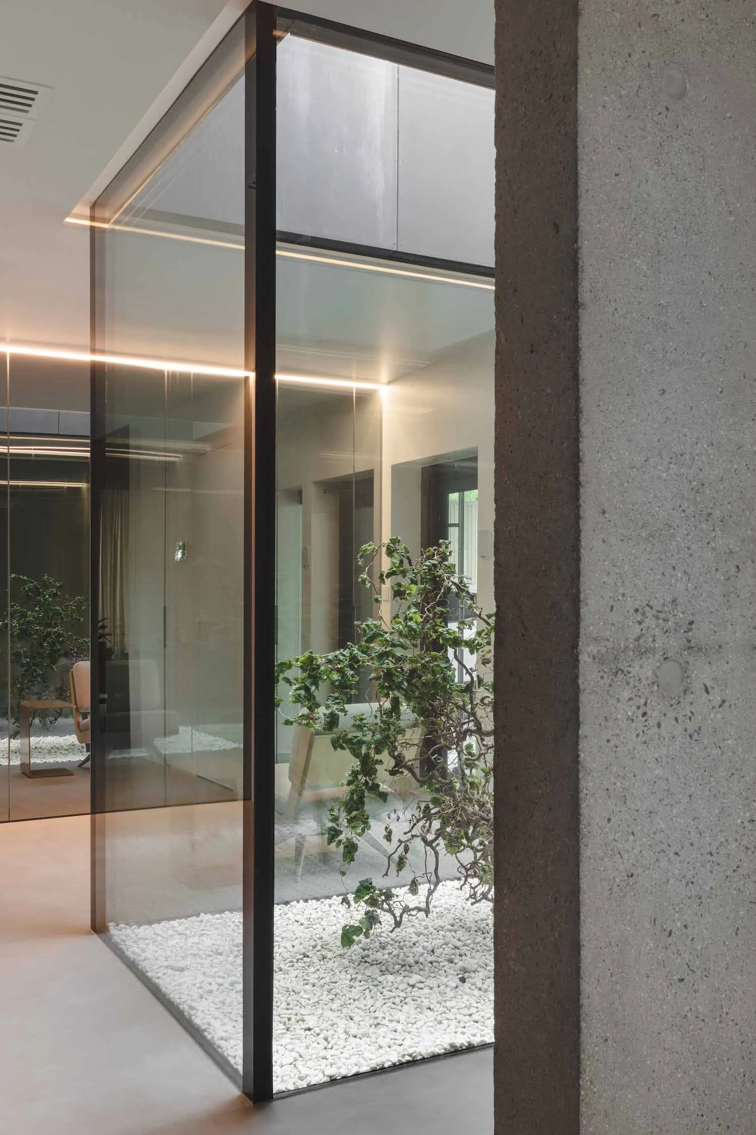 Minimalist office space featuring glass walls and concrete elements.