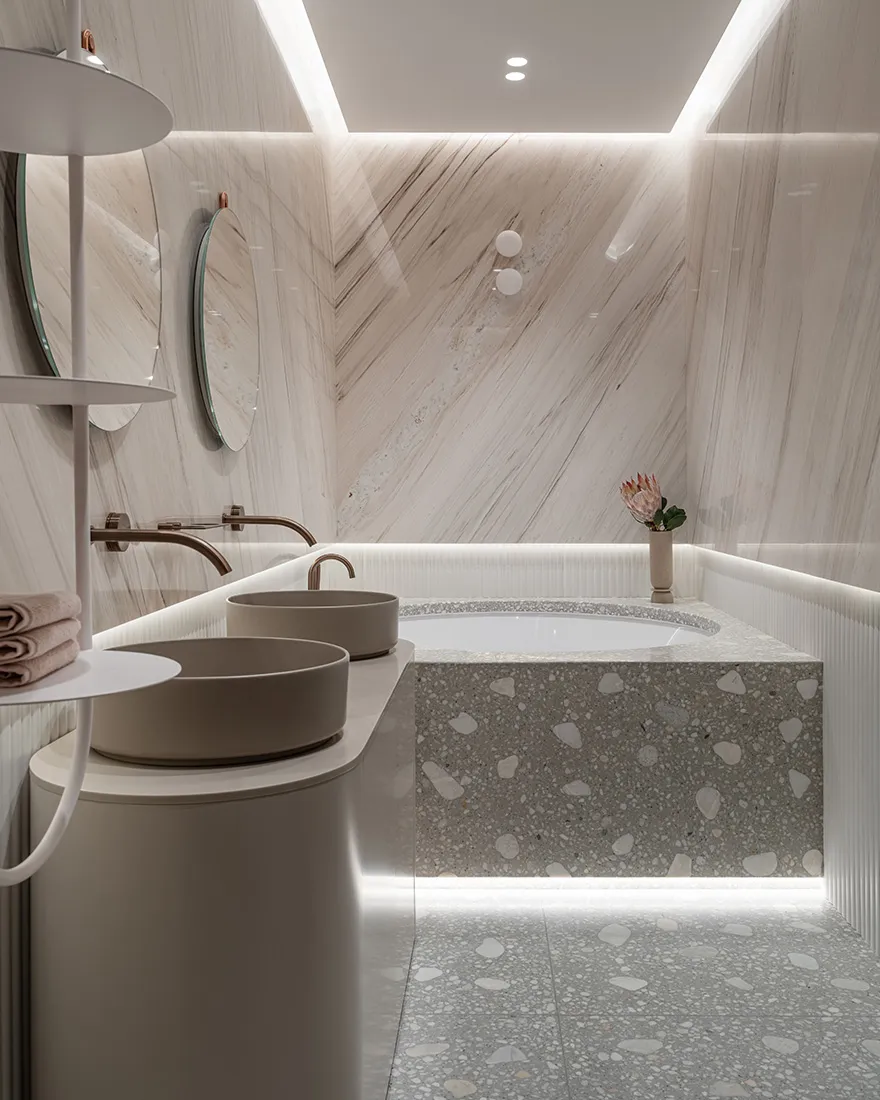 Modern minimalist bathroom featuring marble walls and a terrazzo-tiled floor with a freestanding tub and dual vanity sinks.