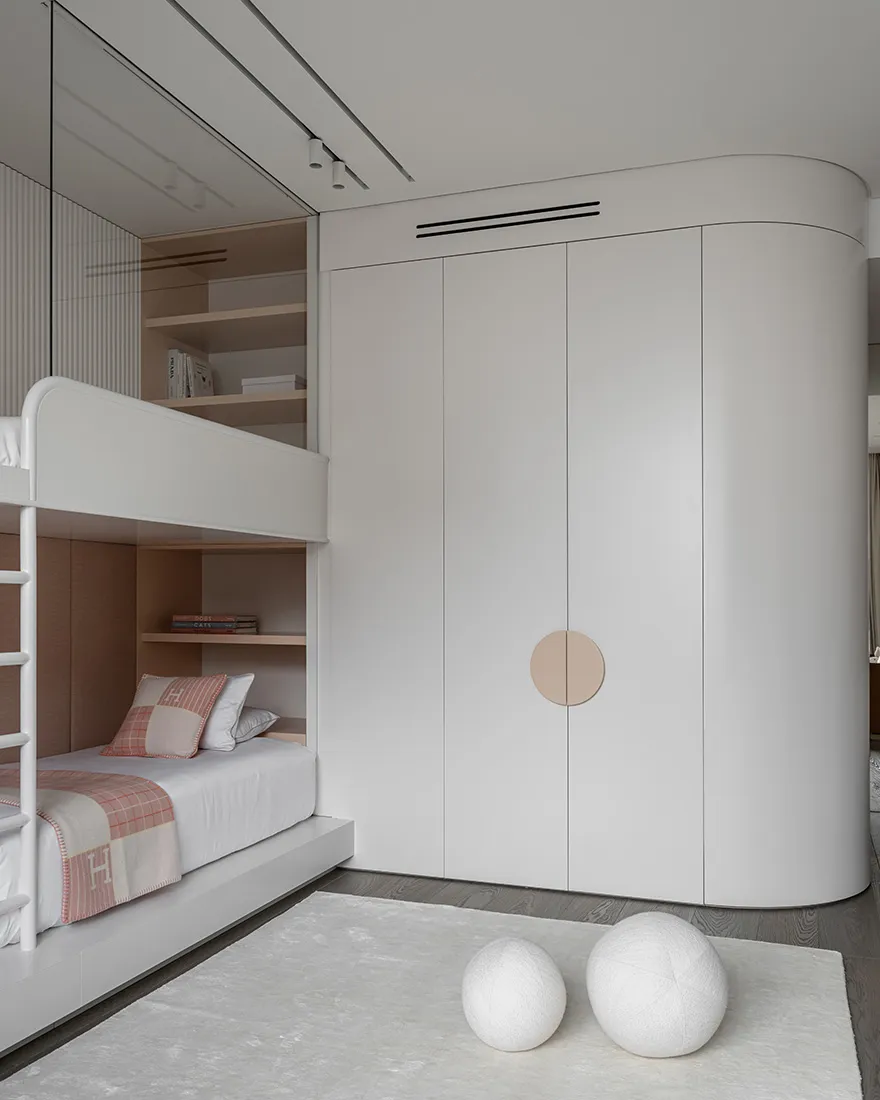 A minimalist bedroom featuring furniture and storage solutions in white.