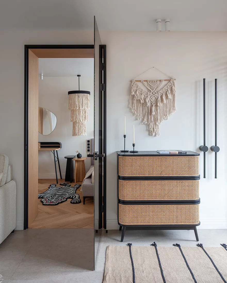 A minimalist bedroom featuring bohemian textiles and a woven chair.