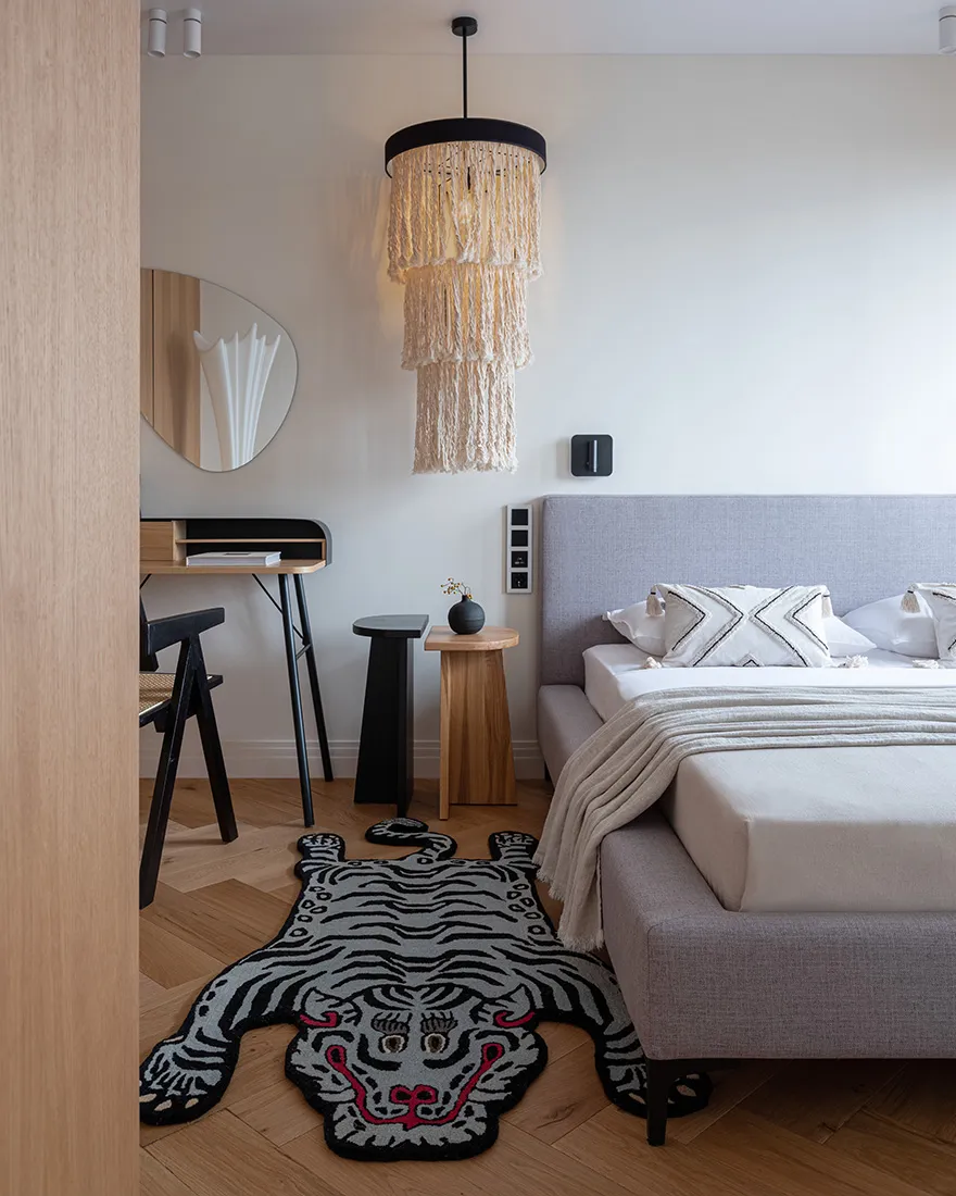 A modern, minimalist bedroom with a draped bed, a tiger-patterned rug, and a modern bed.