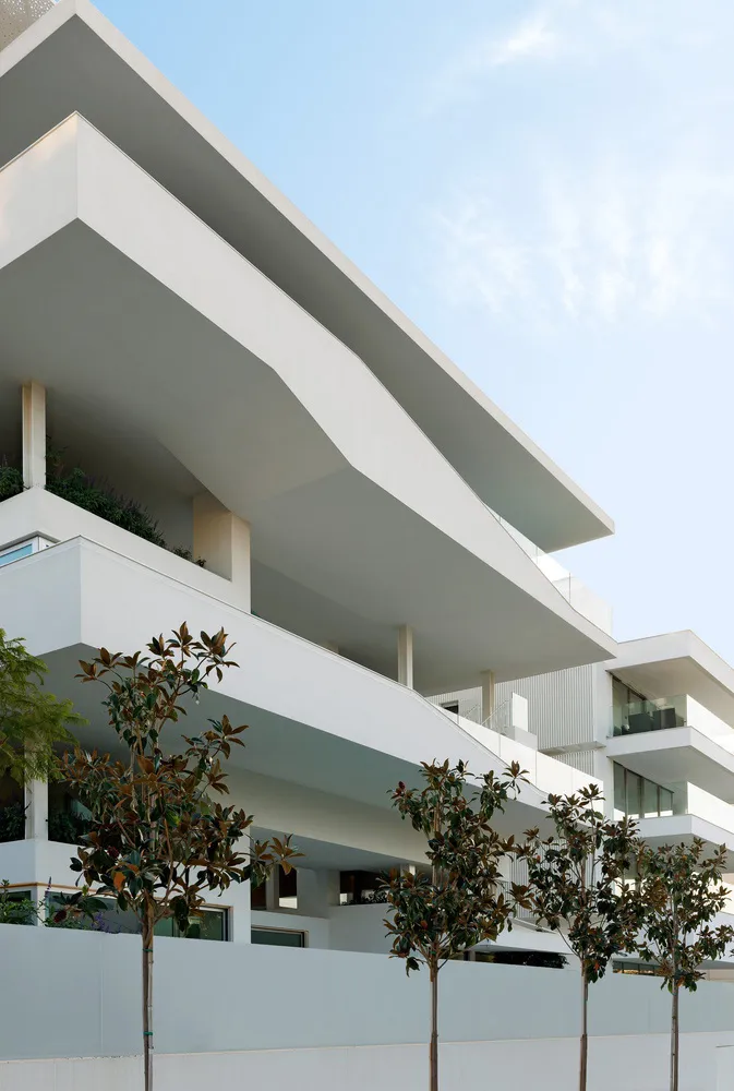 A modern, mixed-use development featuring white concrete structures with glass elements.