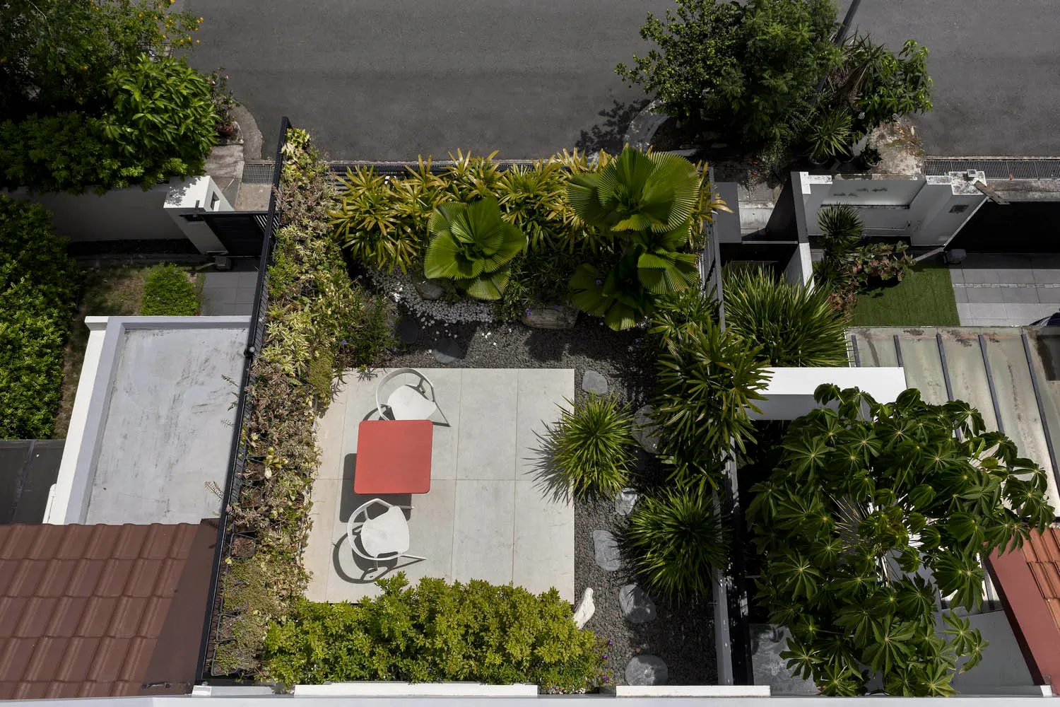 A modern design featuring concrete patio, rocks, and lush green plants on a rooftop or courtyard.