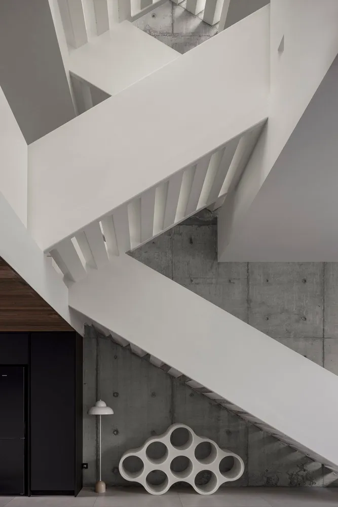 Modern minimalist white space featuring concrete walls and white staircase.