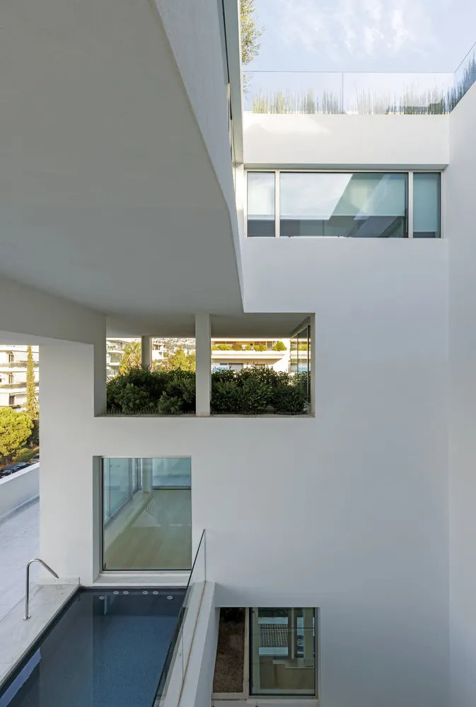 Modern residential architecture with minimalist design, featuring white concrete walls and sleek lines.