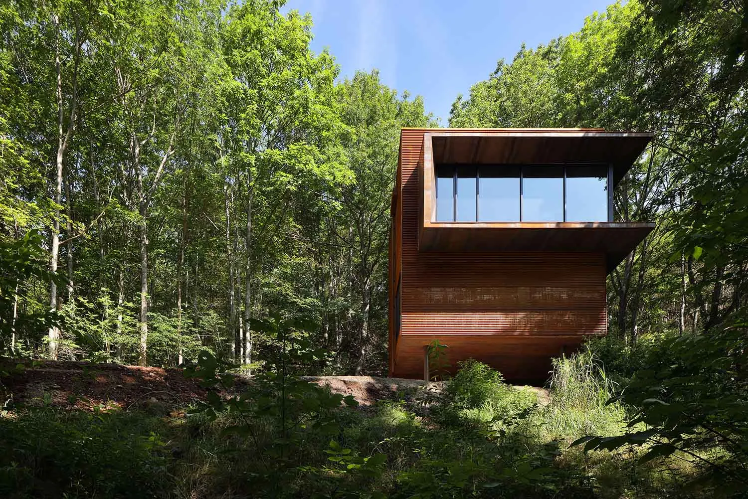 Modern minimalist cabin in the woods with large glass windows.