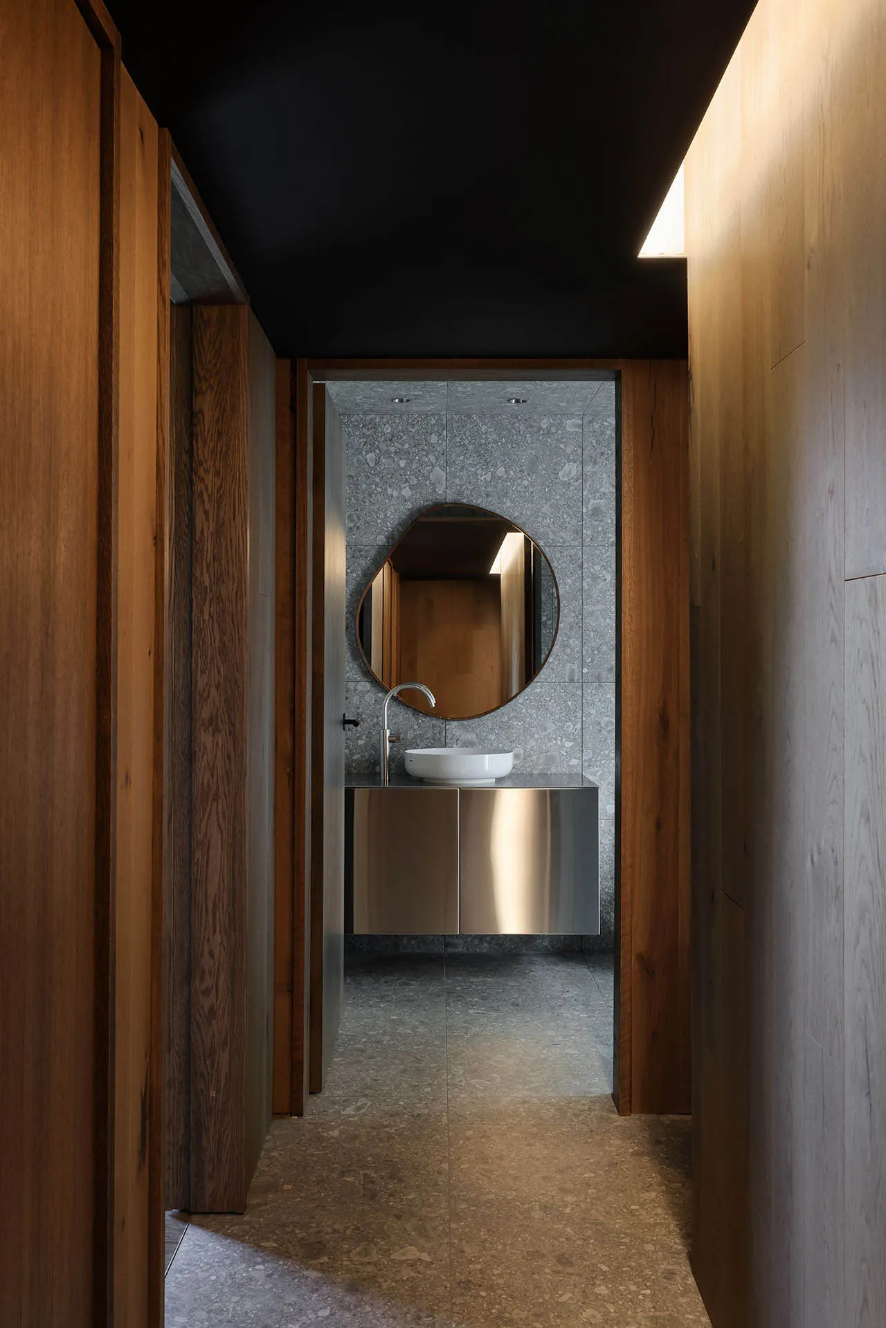 Modern minimalist bathroom with concrete walls and floor, white sink, and round mirror.