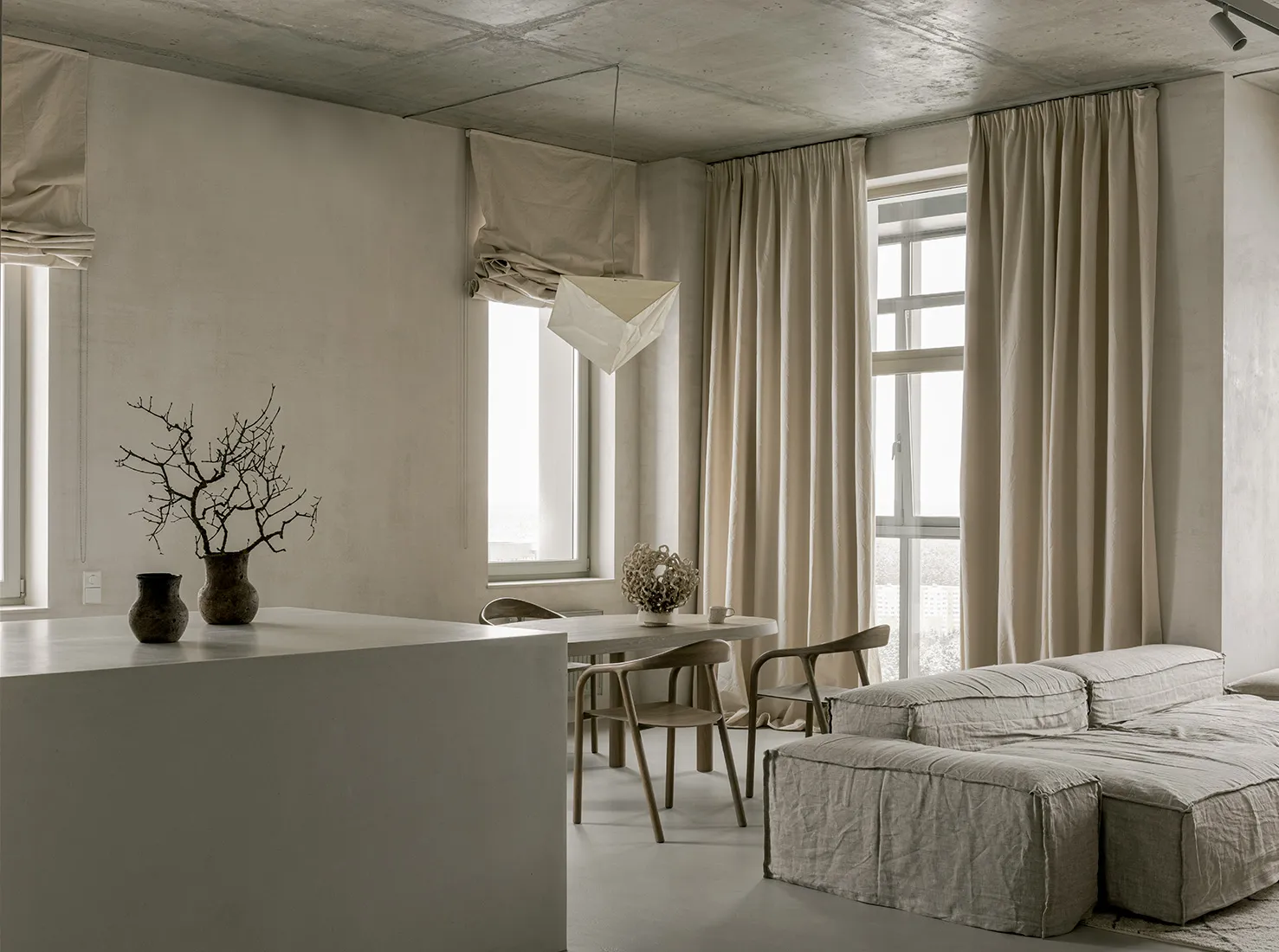 A minimalist living room with fabric curtains and a concrete ceiling
