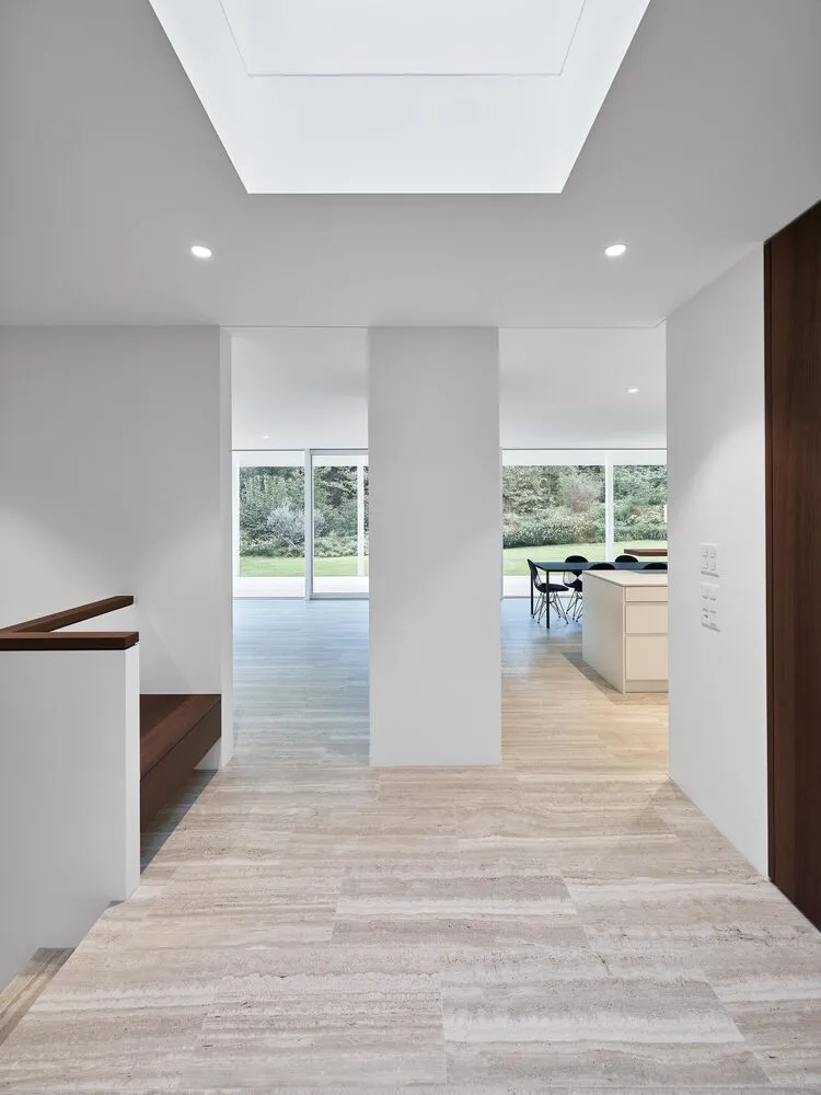 Interior view of a modern kitchen and dining area with marble floors and white walls.