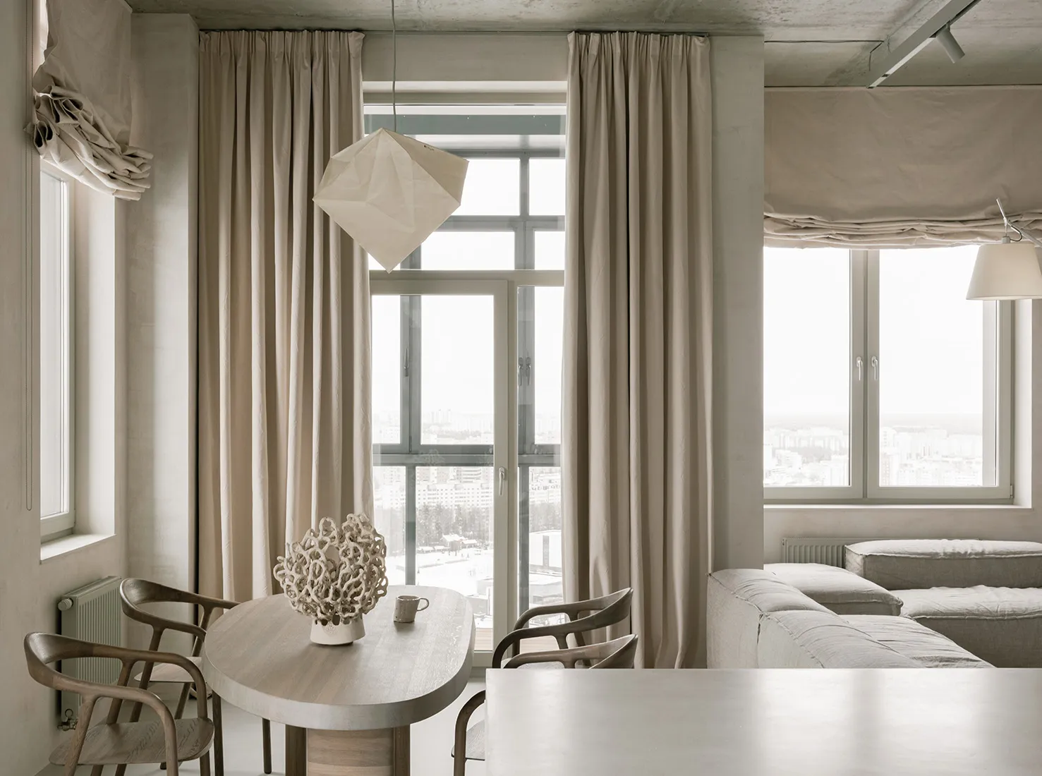 A modern dining room with neutral tones and a round wooden table.