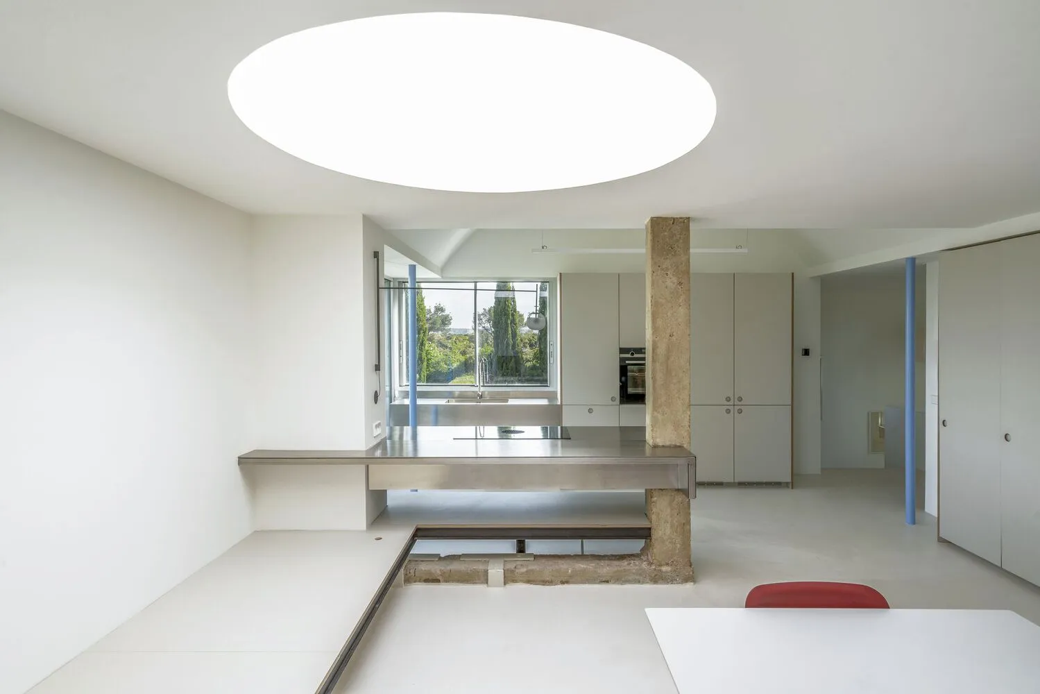 Modern kitchen interior featuring minimalist design with concrete countertops and white walls and flooring.