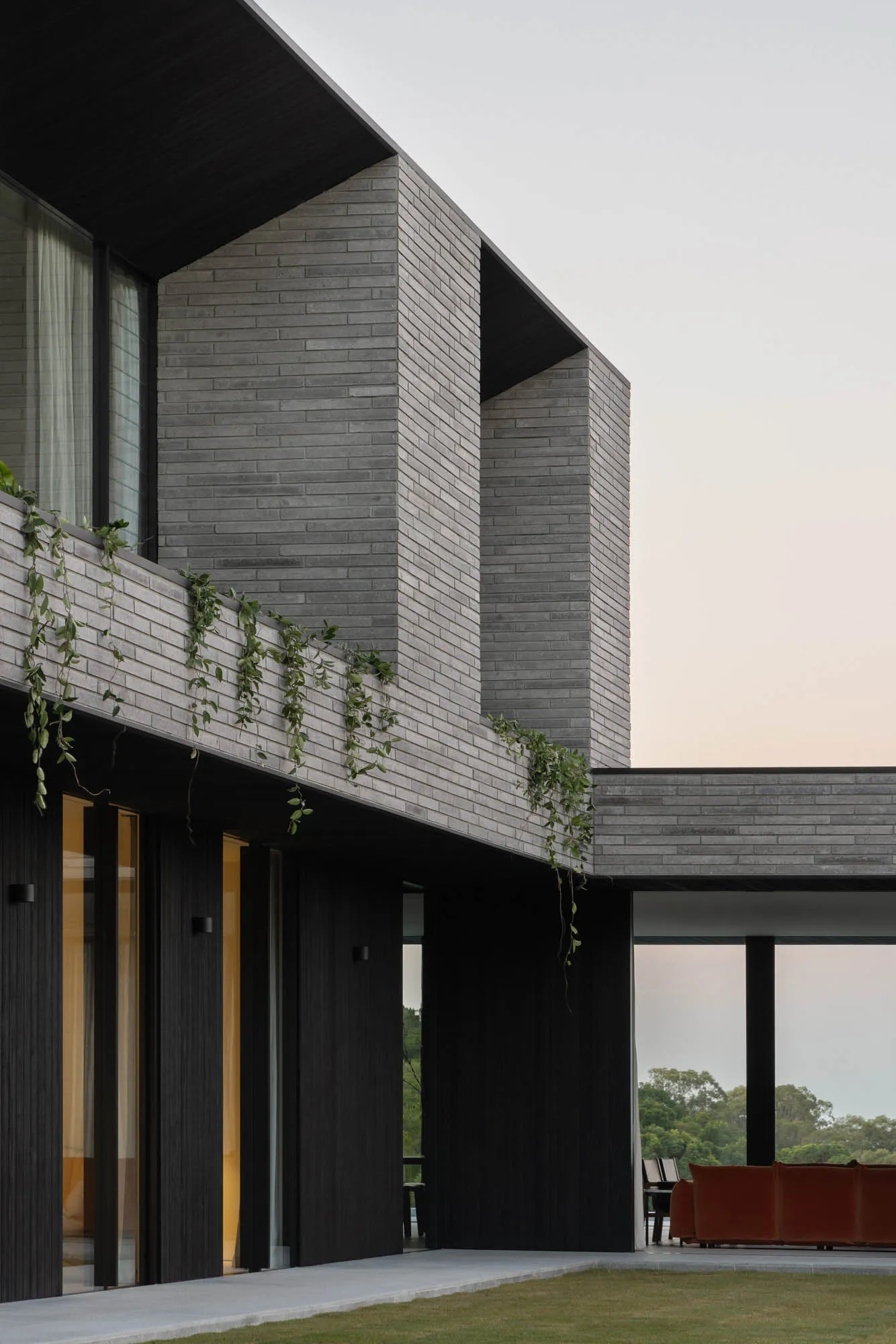 Modern residential building exterior with brick and concrete materials and climbing plants