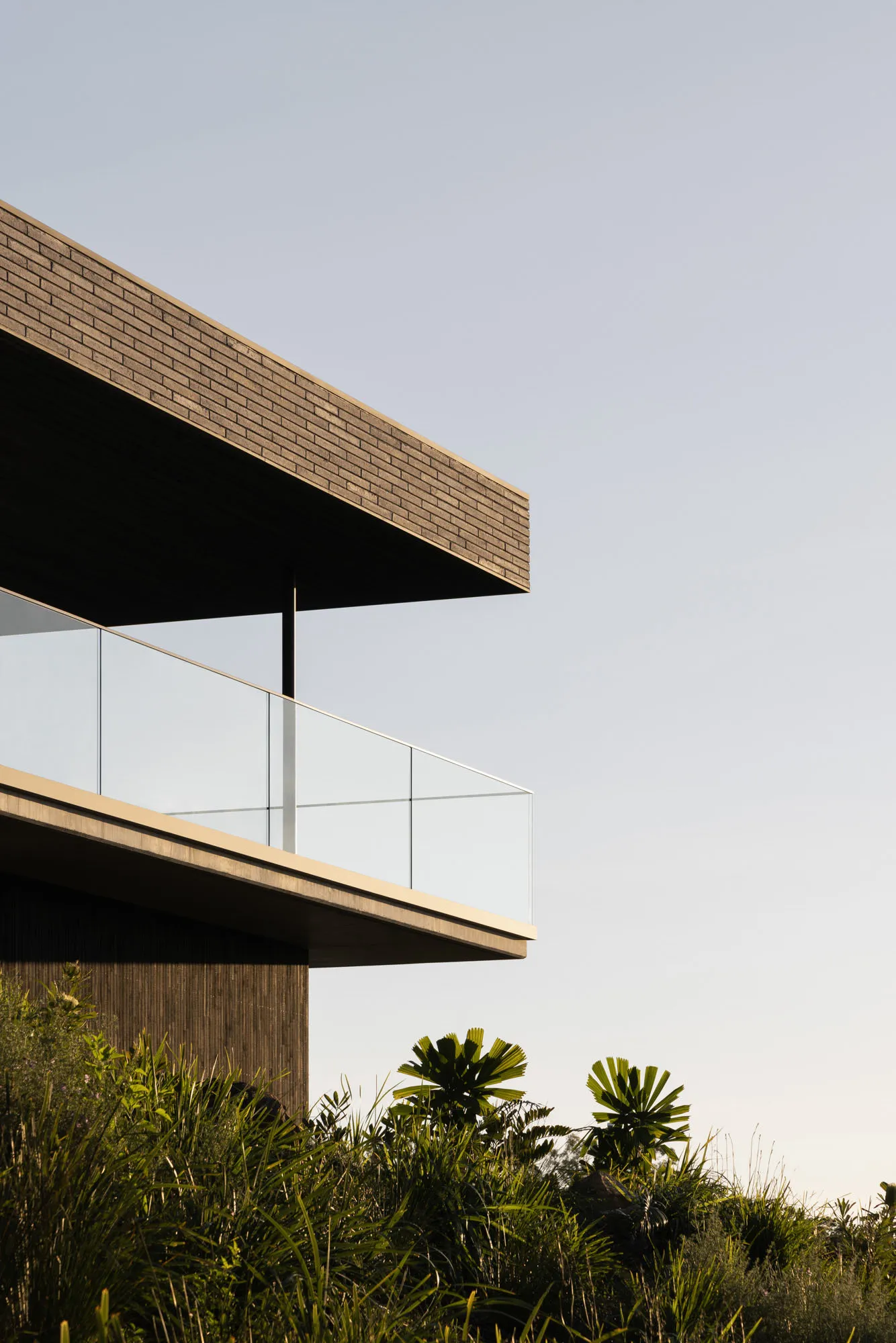 Modern house with glass and brick exterior, featuring a large balcony.
