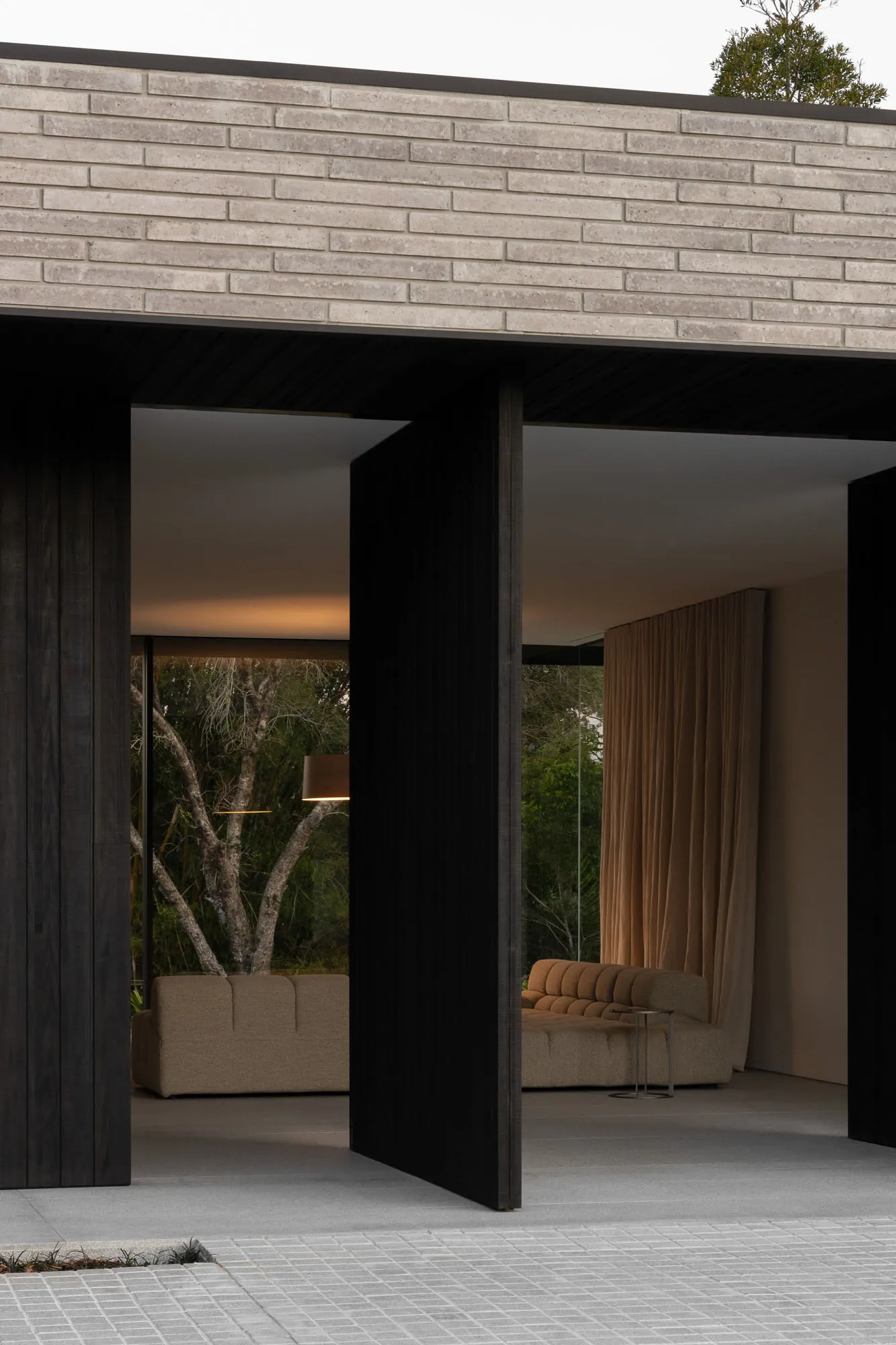 A modern living room with concrete walls and floor, featuring a cozy sofa and floor lamp.