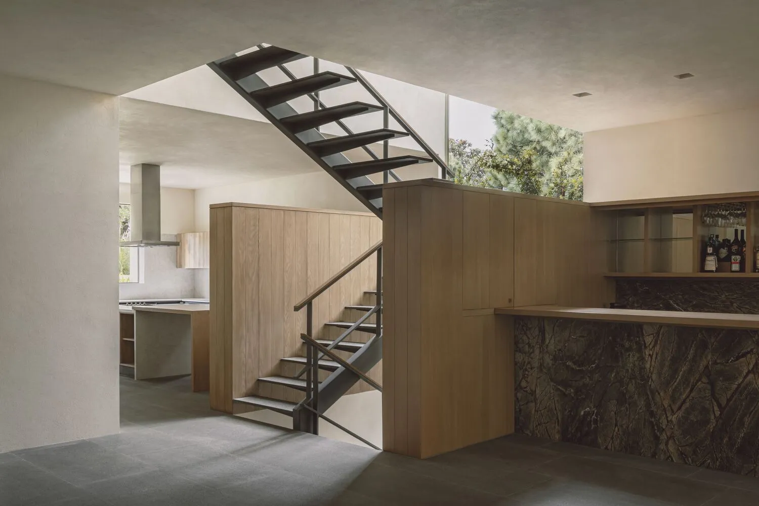 A modern residential interior featuring a metal staircase, wooden walls, and a marble countertop.