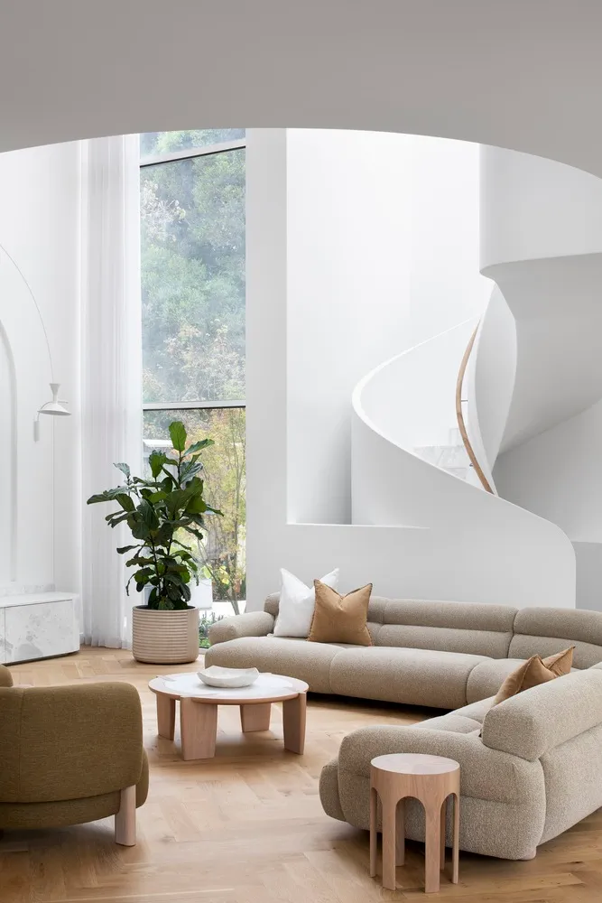 A modern living room featuring neutral-colored fabric furniture, a potted plant, and wooden accents.