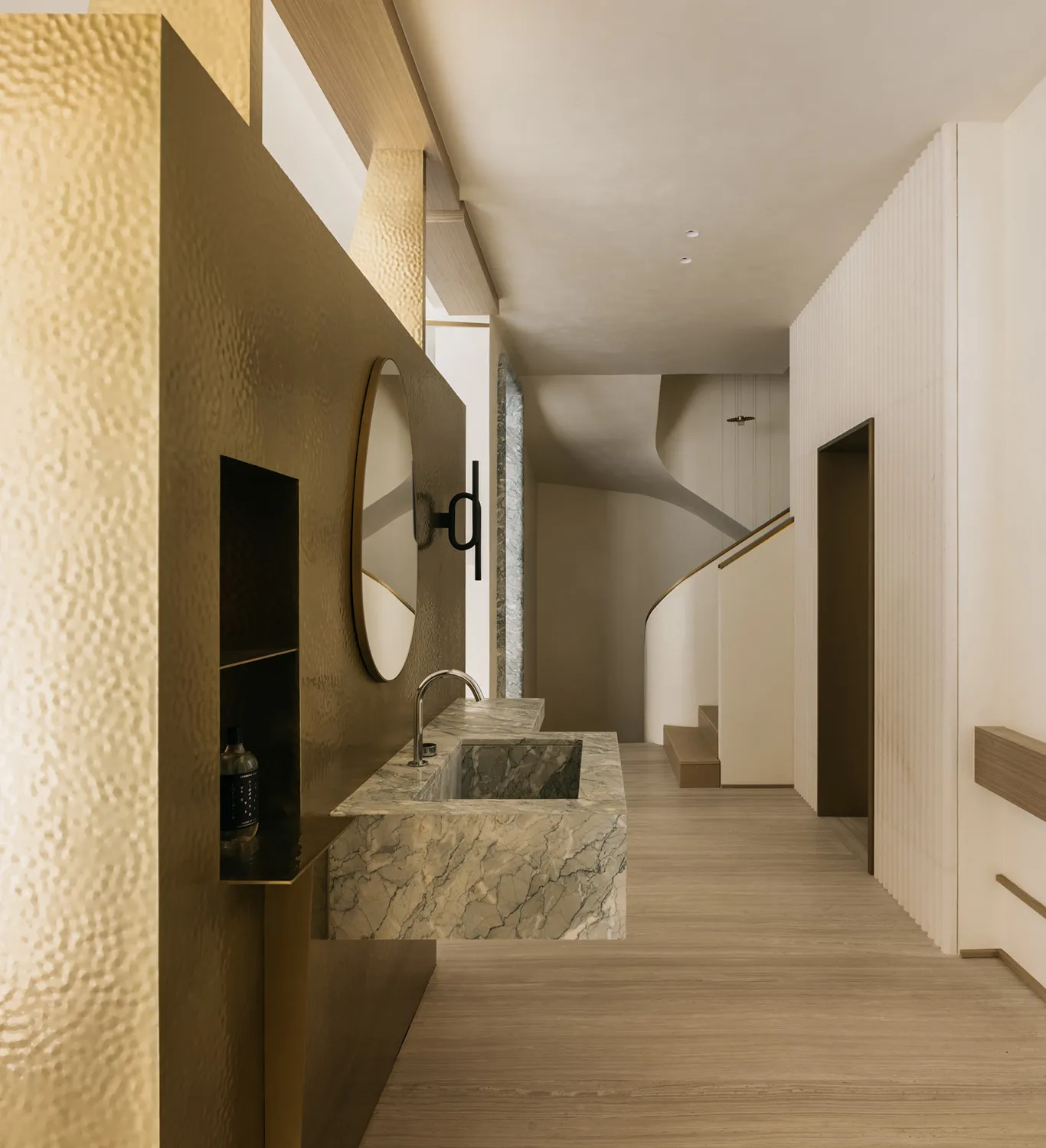 A modern bathroom with a marble countertop and brass vertical accents.