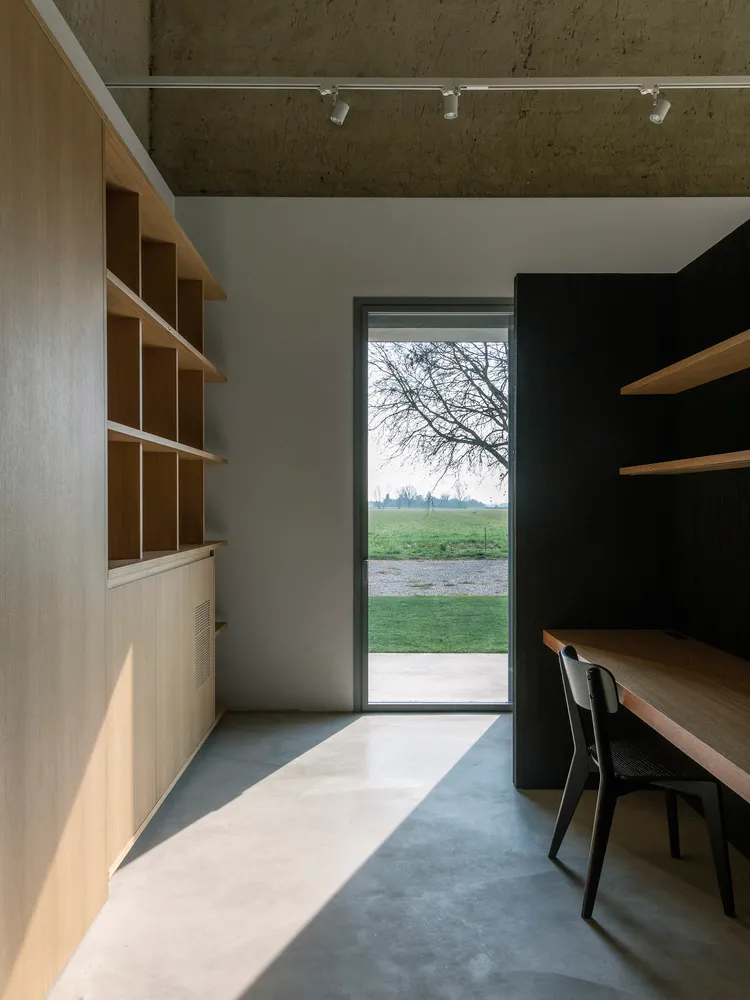 Modern home office with industrial design elements, featuring wooden shelves and concrete floor.