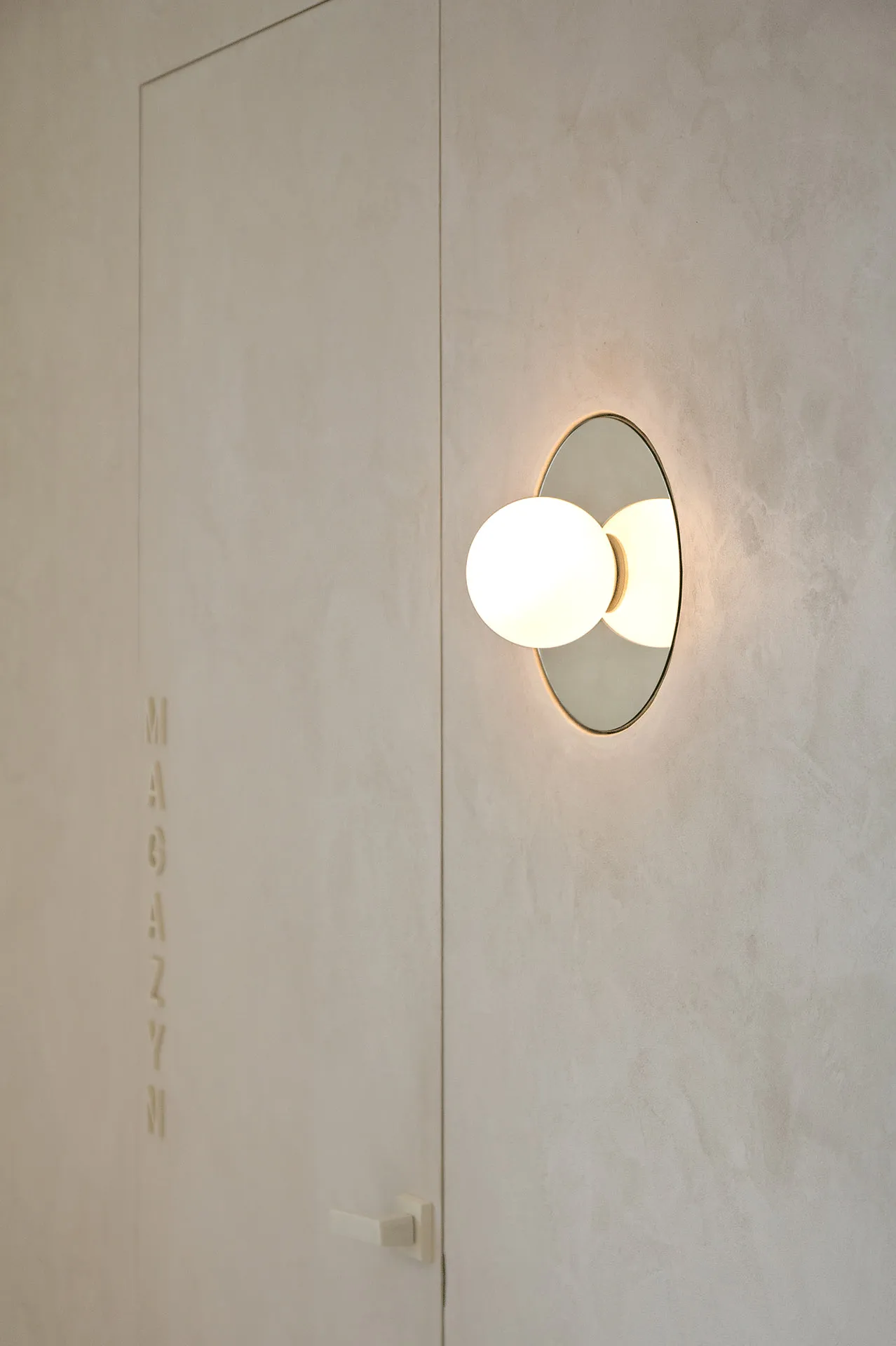 A minimalist wall light fixture embedded in a textured wall, casting a warm glow.