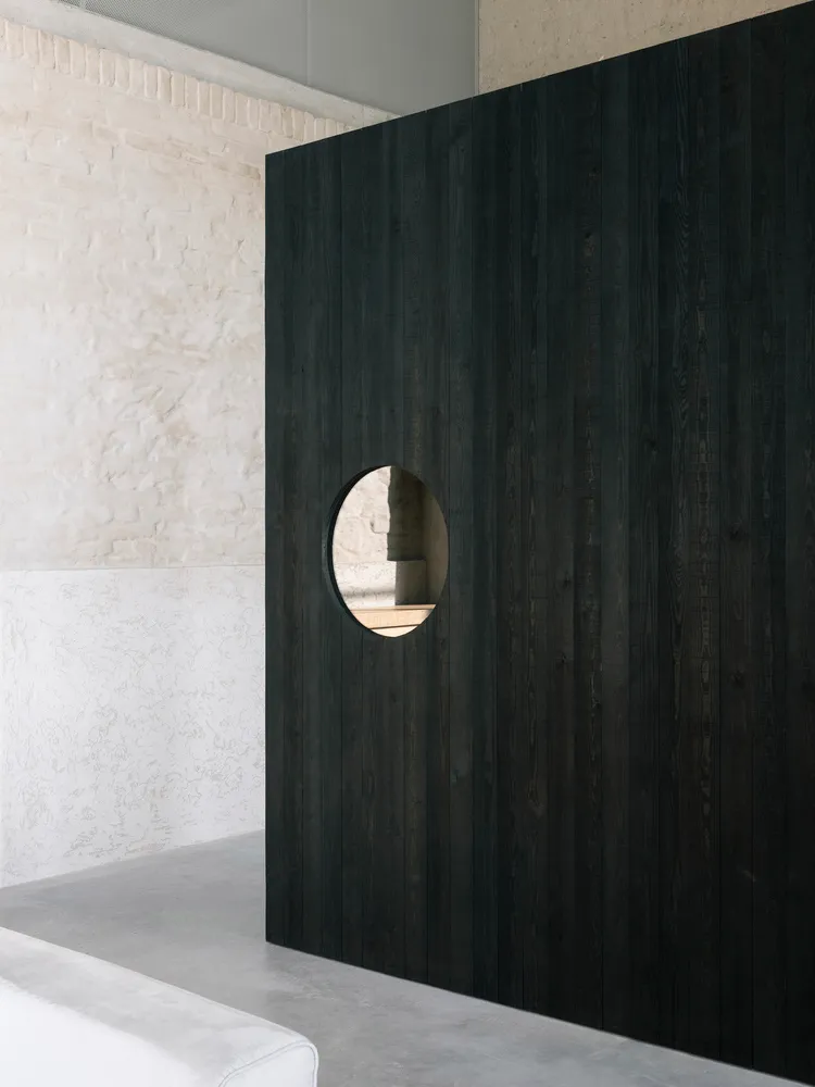 A minimalist interior design with a dark wooden wall featuring a circular cutout.