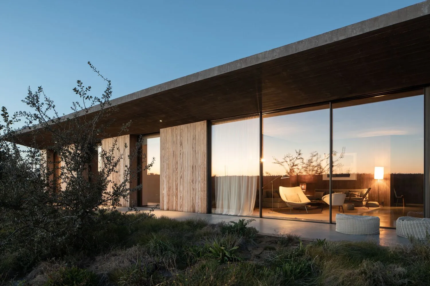 Modern residential exterior featuring glass walls and wooden elements.