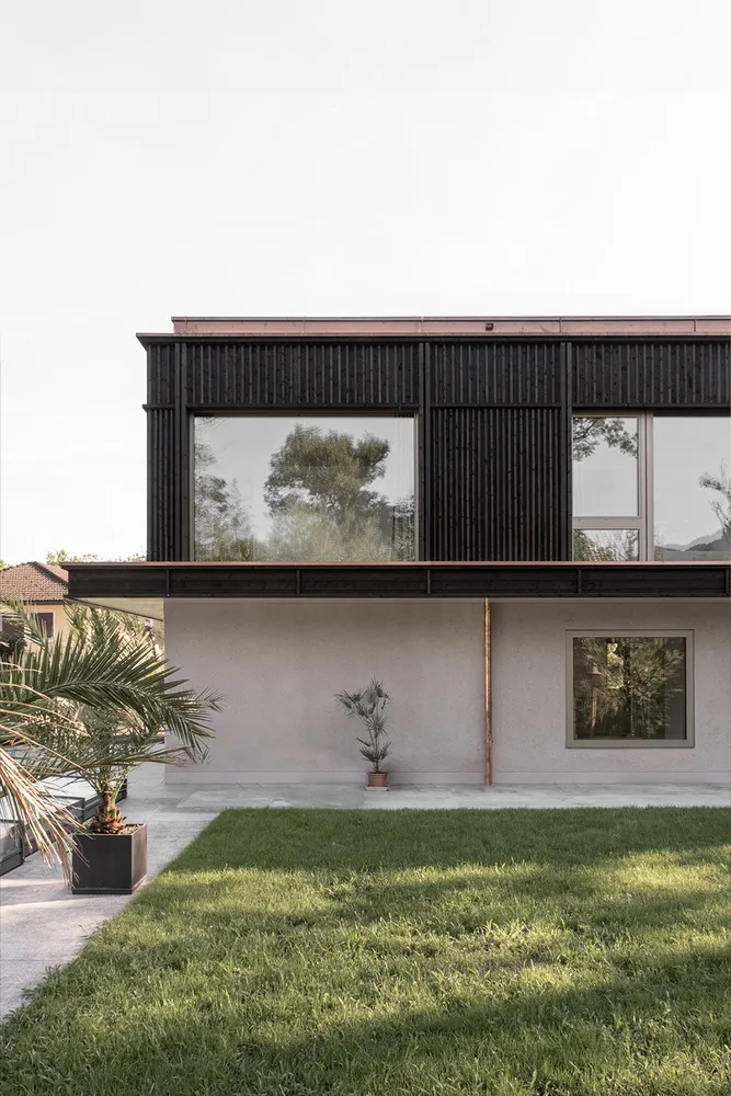A modern house with a concrete exterior featuring large windows and a minimalist design.