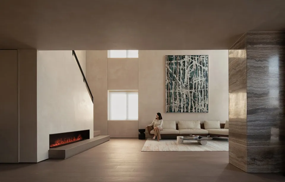 A modern minimalist living room featuring concrete and marble materials, with a woman sitting on a sofa.