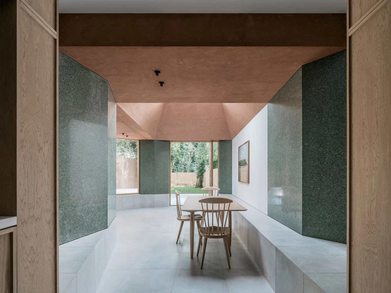 Modern dining room with concrete and ceramic walls, wooden table and chairs, and large windows