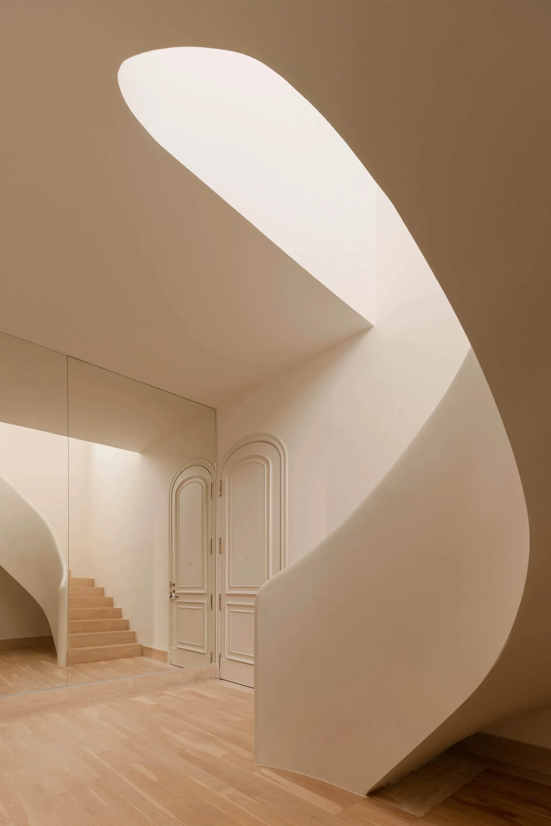 A modern, white, space with curved, white walls and a spiral staircase.