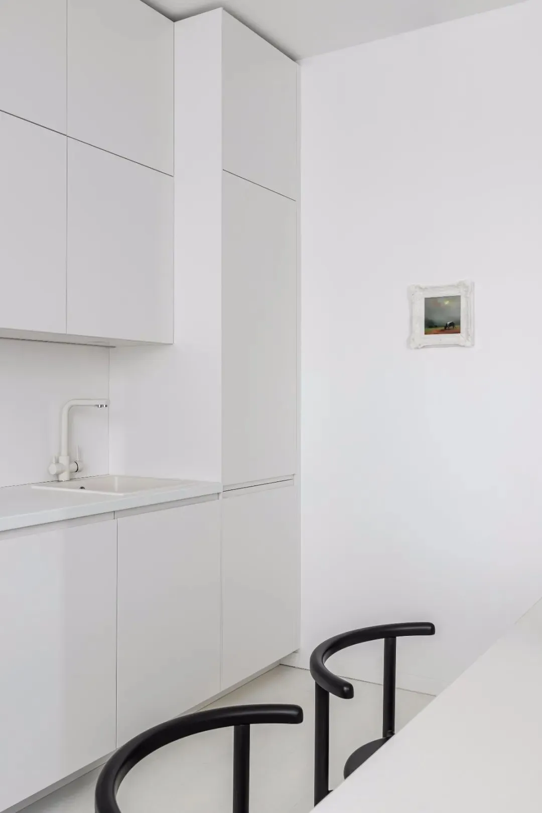 Modern minimalist kitchen featuring sleek white cabinets and minimalist design.