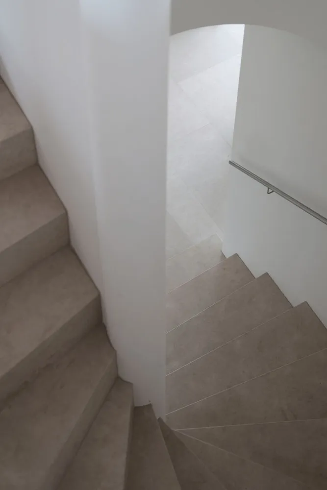 A modern staircase with minimalist design features concrete steps and a white wall.