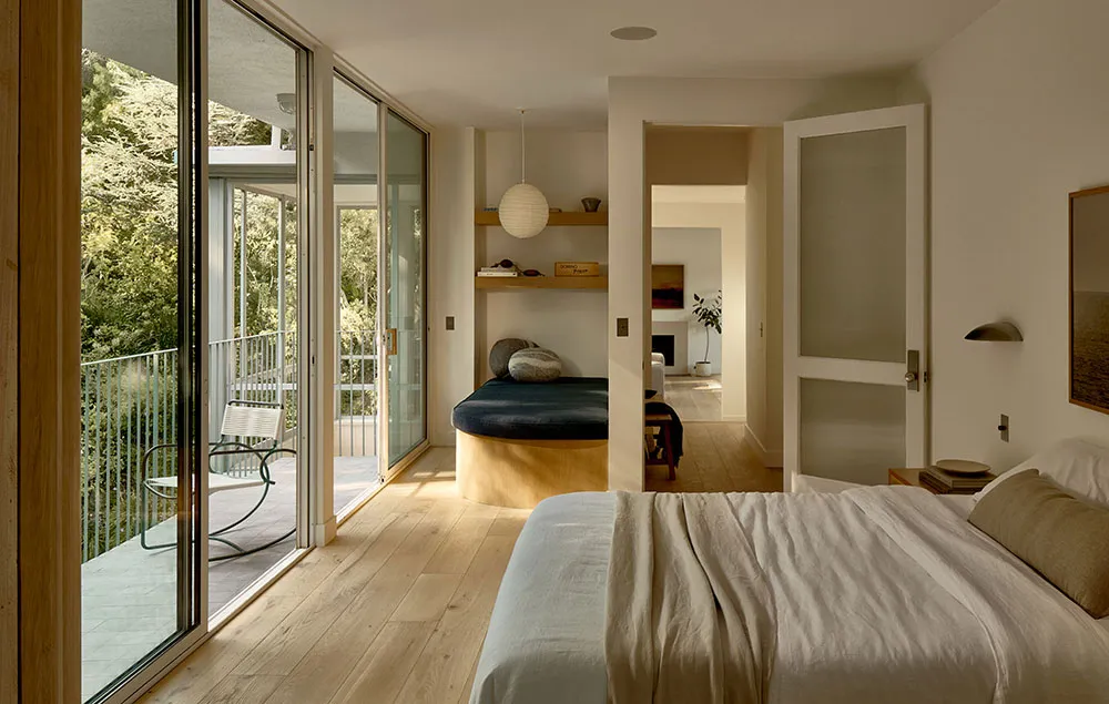 Minimalist bedroom with a white bed and wooden floor.