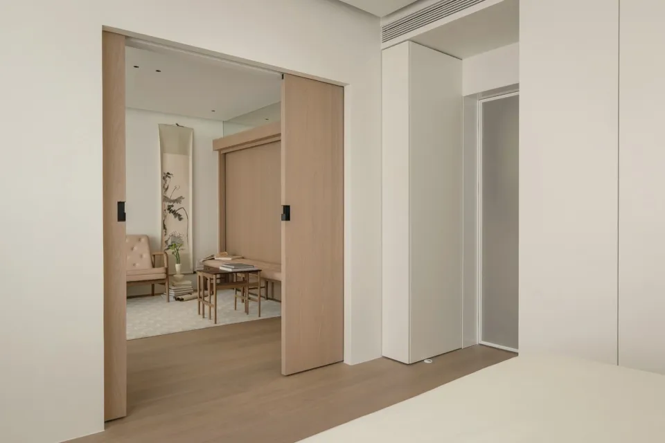 A minimalist bedroom featuring wooden furniture and a sliding door.
