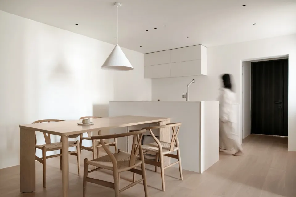 A modern minimalist kitchen with wooden furniture and white appliances.