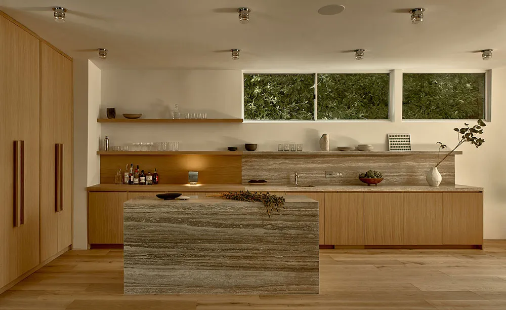 Modern minimalist kitchen featuring wood cabinetry, marble countertops, and a central marble island.