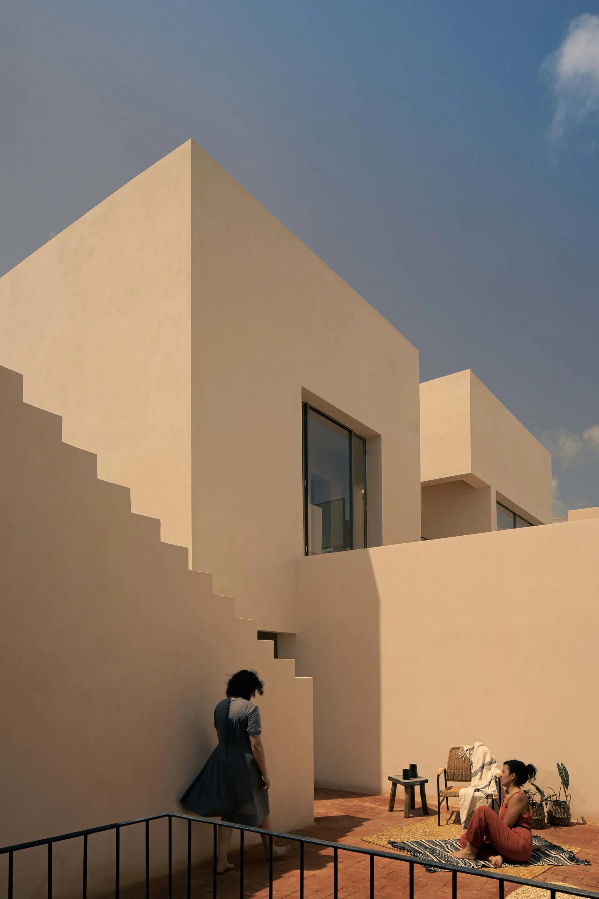 Modern minimalist architecture featuring sandstone buildings with geometric shapes and large windows.
