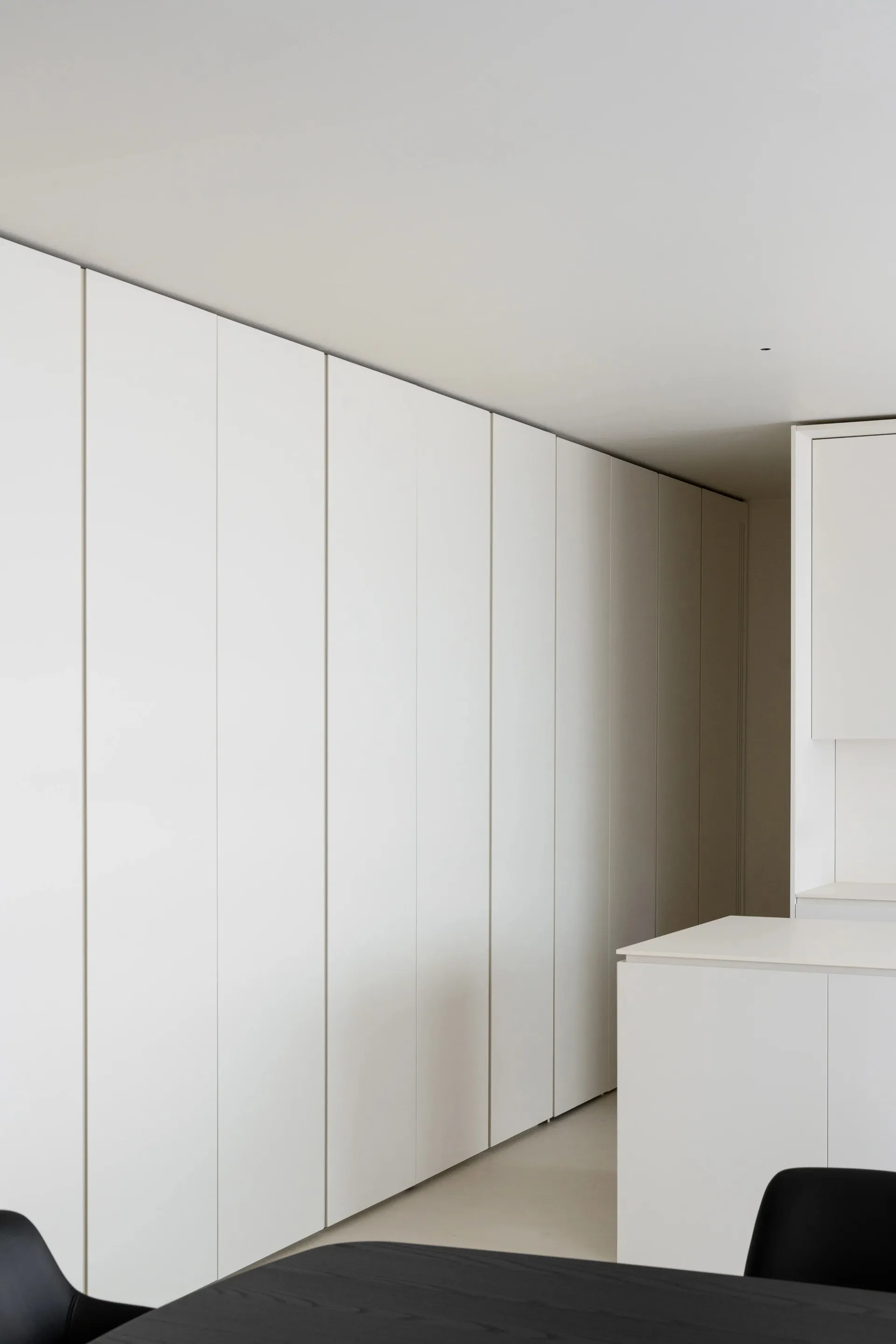 A minimalist bedroom featuring white cabinets against a white wall and floor.