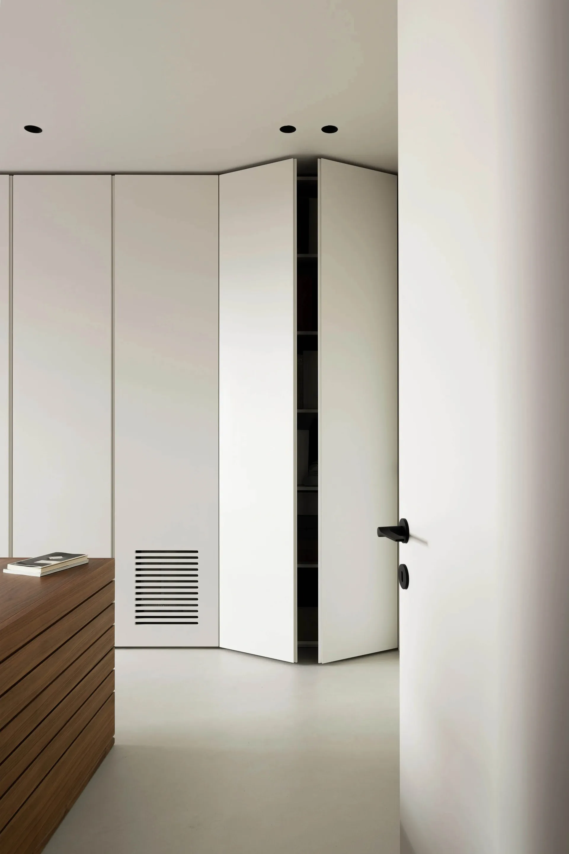 Modern interior of a white closet with wood accents and ventilation grille.