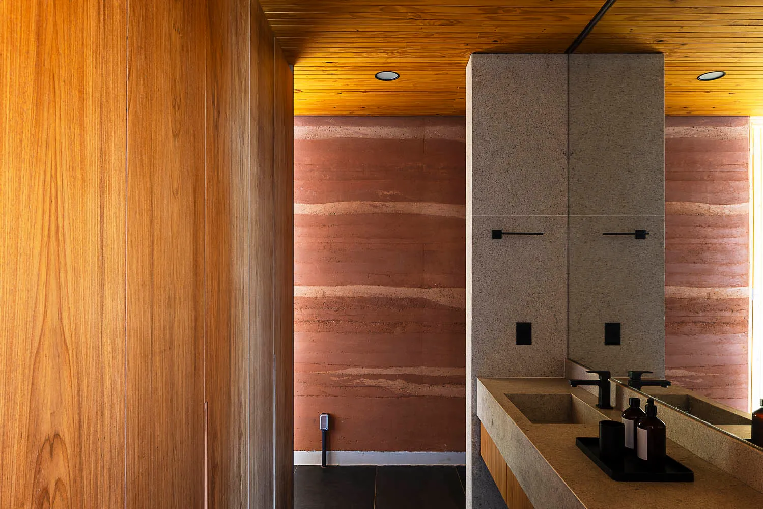 A modern bathroom featuring a concrete floor and walls, with a wooden ceiling and minimalist design.