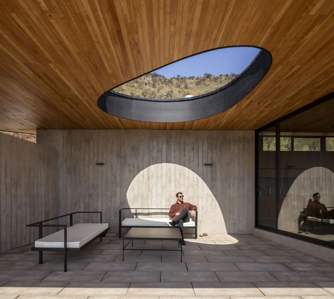 A modern minimalist living room with concrete walls and a circular window