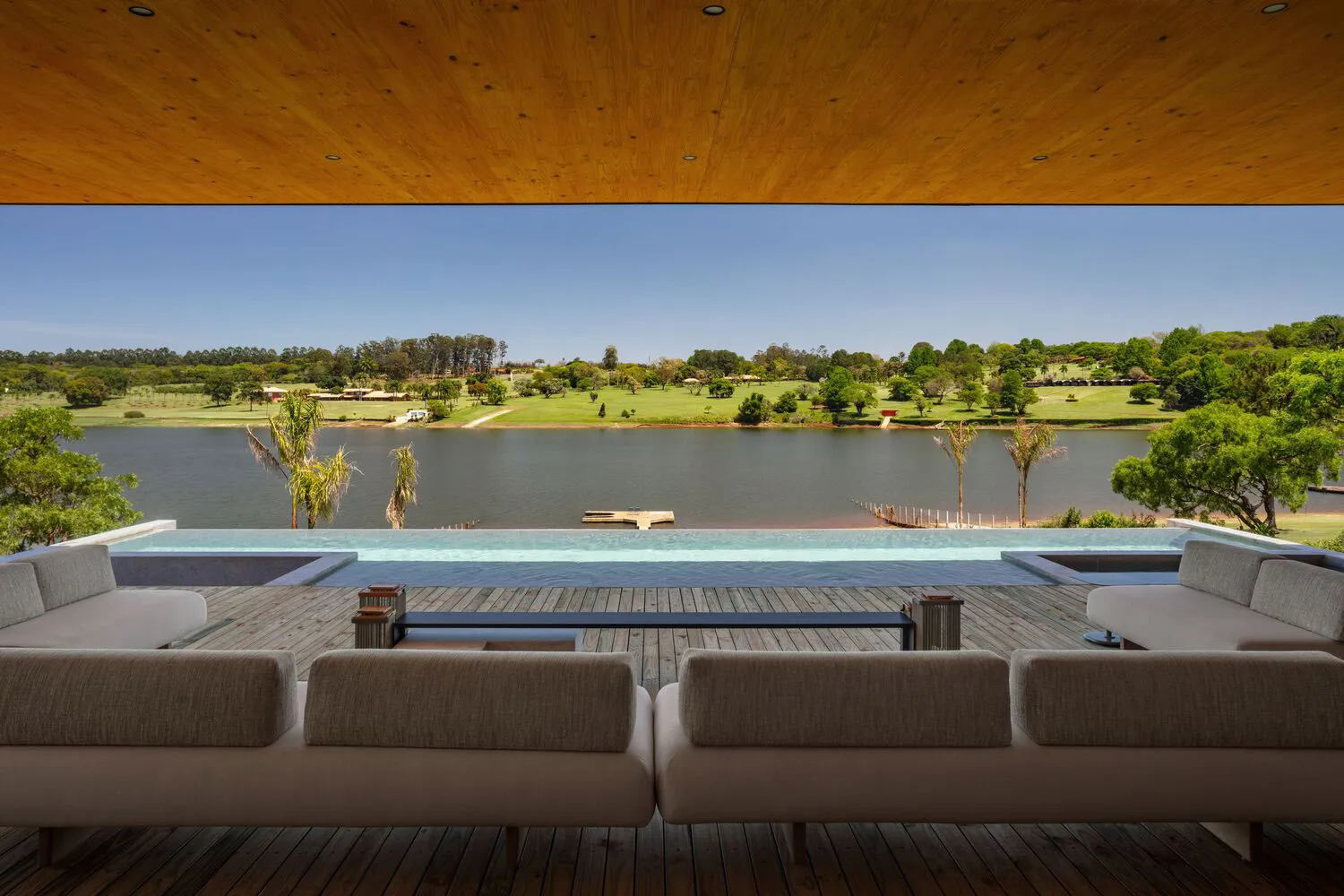 A modern, spacious living room with a large sofa overlooking a serene lake.